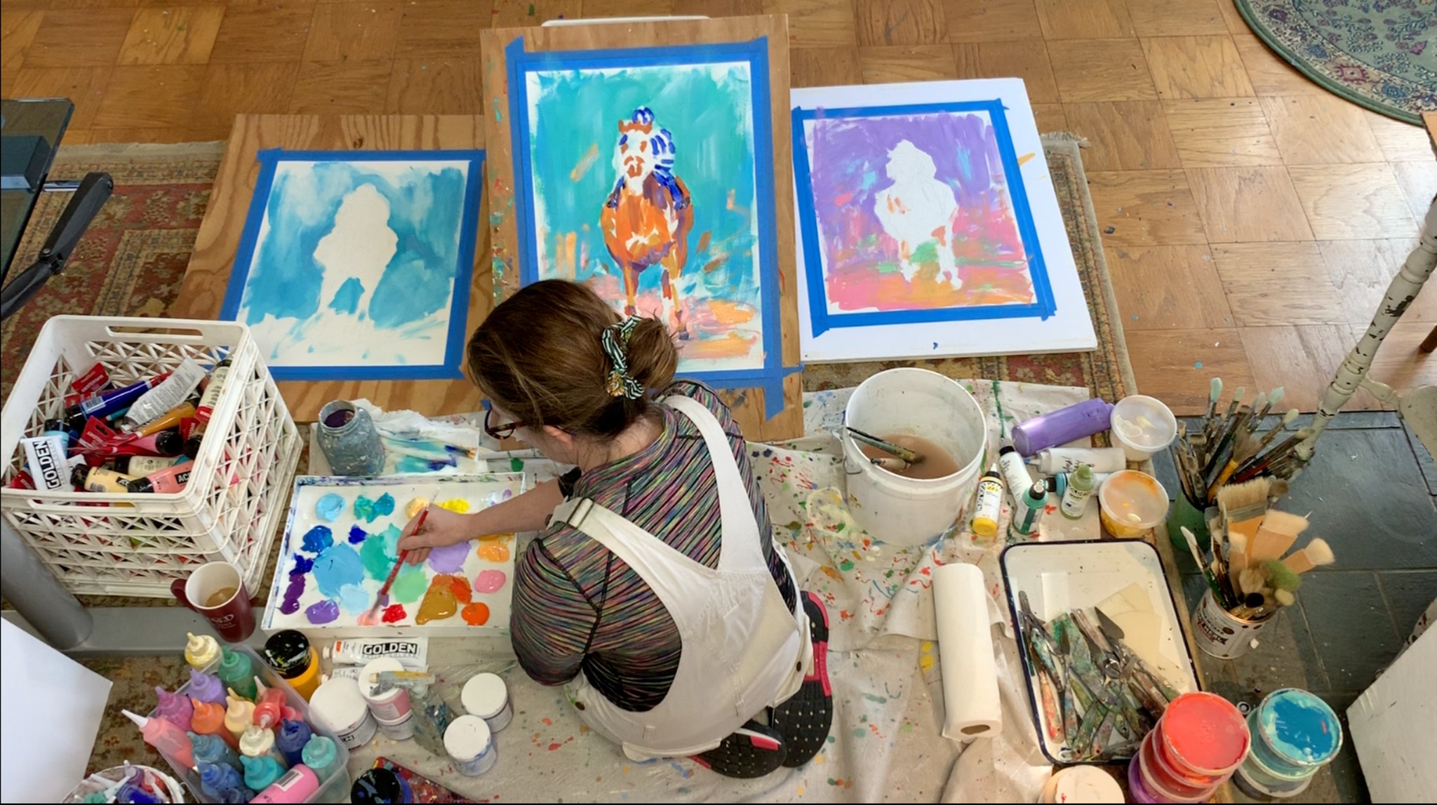 Lisa mixing colors while painting on the studio floor